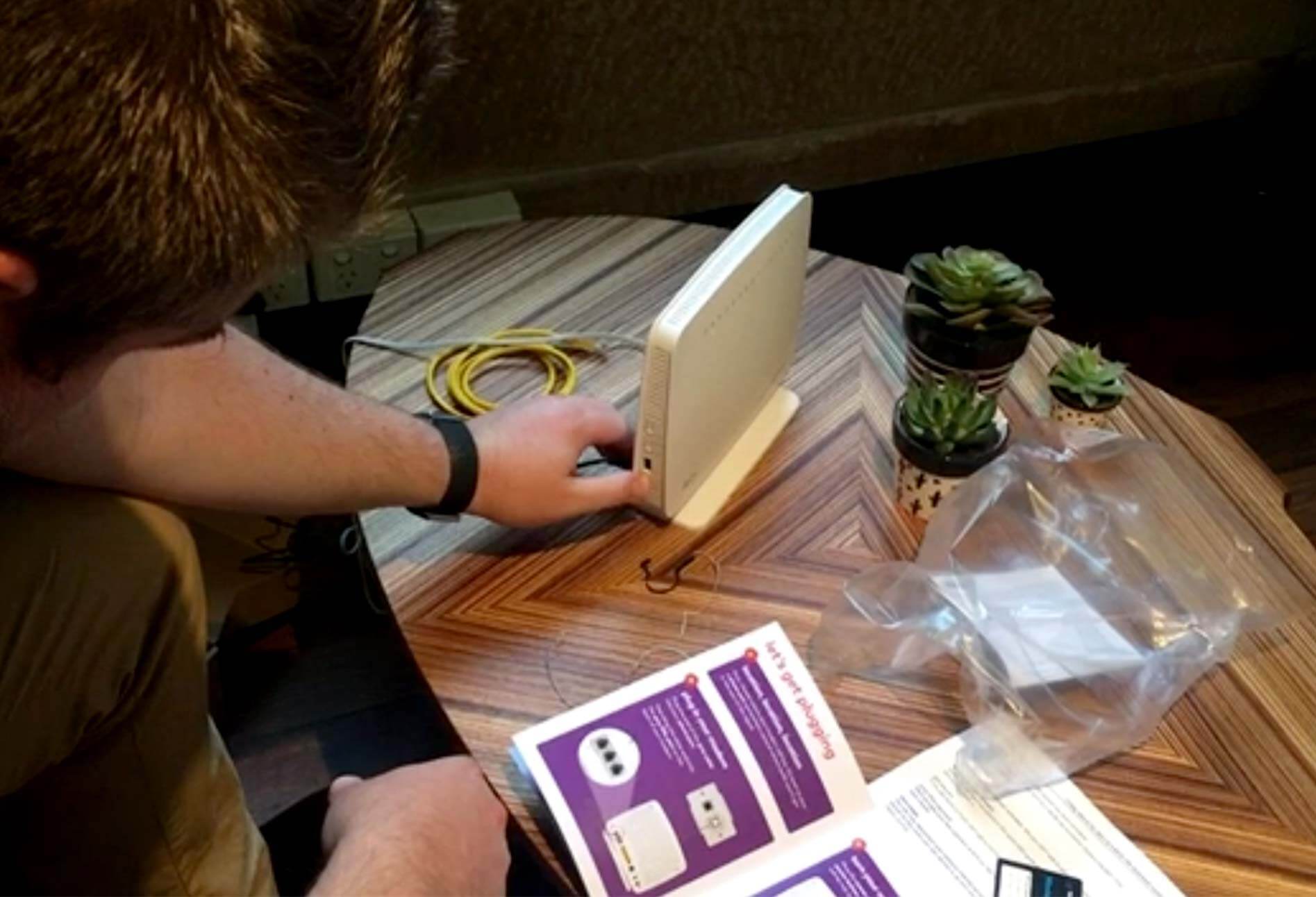 Image of a man trying to set up a modem on a table with cables on a table
